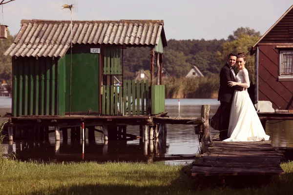 Bride and groom on wooden bridge near lake — Stock Photo, Image