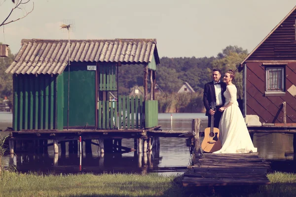 Noiva e noivo na ponte de madeira perto do lago — Fotografia de Stock