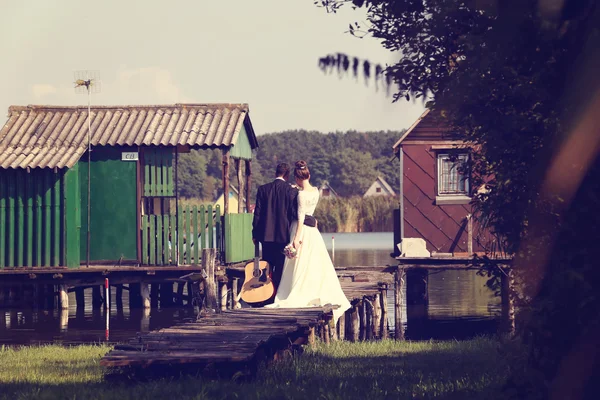Sposo e sposo sul ponte di legno vicino al lago — Foto Stock