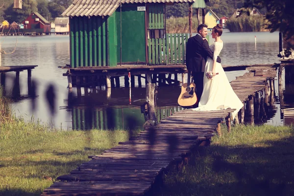 Novia y novio en puente de madera cerca del lago — Foto de Stock