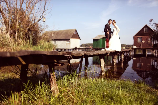 Mariée et marié sur un pont en bois près du lac — Photo