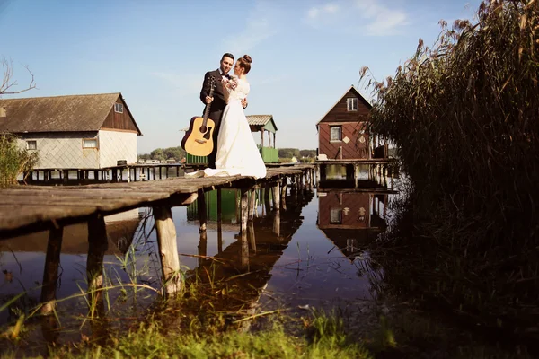 Bride and groom on wooden bridge near lake — Stock Photo, Image