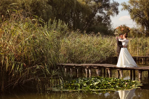 Bruid en bruidegom op houten brug — Stockfoto