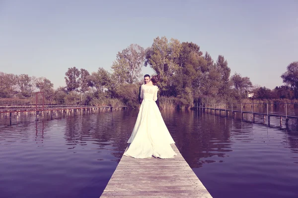 Pareja nupcial en puente de madera en el lago —  Fotos de Stock