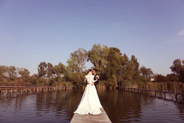 Bridal couple on wooden bridge at lake — Stock Photo, Image