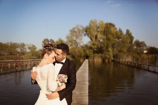 Bridal couple on wooden bridge at lake — Stock Photo, Image