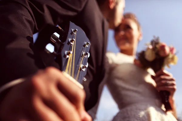 Groom kissing the bride and holding a guitar Stock Picture