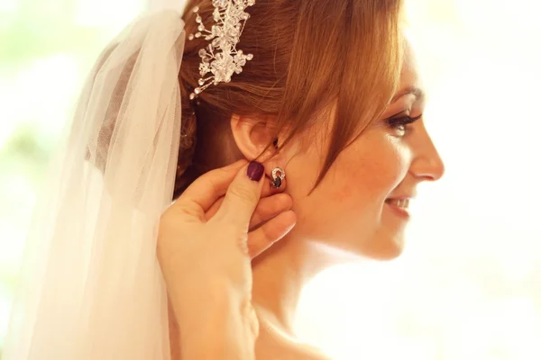 Mains aidant la mariée avec des boucles d'oreilles — Photo