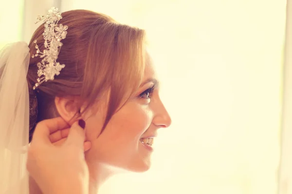 Mains aidant la mariée avec des boucles d'oreilles — Photo