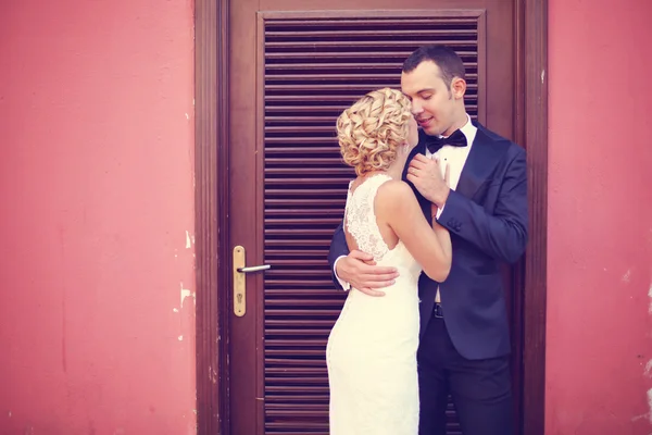 Noiva e noivo abraçando perto da porta — Fotografia de Stock