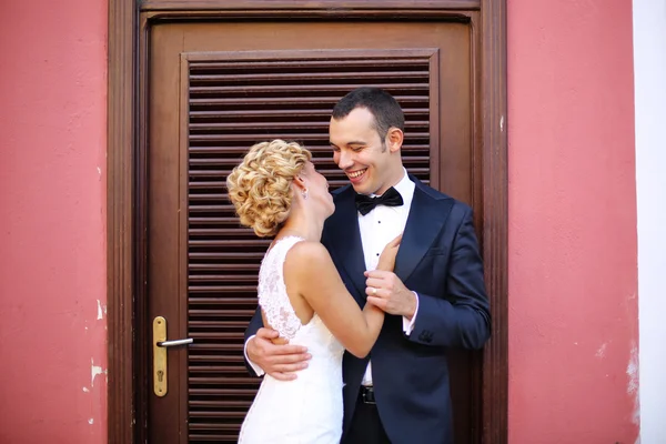 Noiva e noivo abraçando perto da porta — Fotografia de Stock