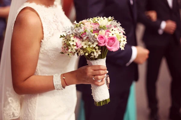 Mãos de uma noiva segurando seu buquê de casamento — Fotografia de Stock