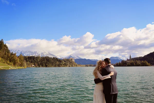 Bride and groom embracing near lake — Stock Photo, Image
