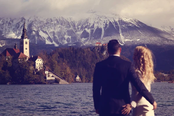 Novia y novio mirando a la isla de Bled Lake, Eslovenia —  Fotos de Stock