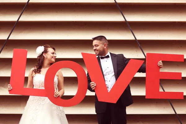 Bride and groom holding big LOVE letters — Stock Photo, Image