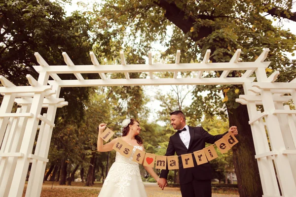 Ženich a nevěsta drží jen vzali znamení — Stock fotografie