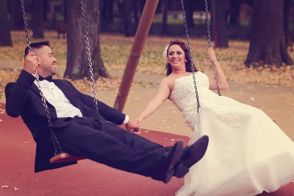 Bride and groom in a swing — Stock Photo, Image