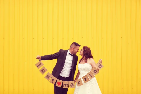 Novia y novio sosteniendo signo de recién casados — Foto de Stock