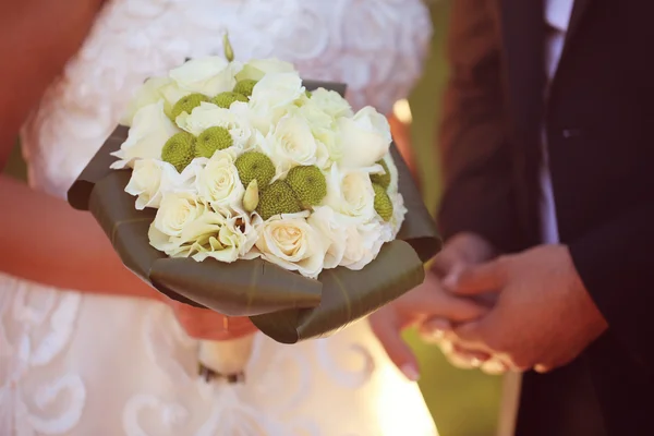 Bruden och brudgummen håller i händerna och en bröllop bukett — Stockfoto