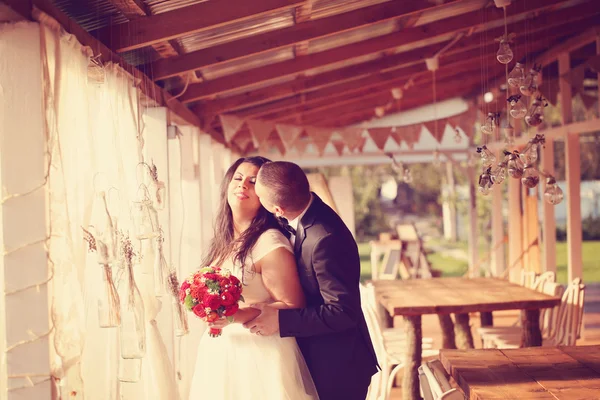 Novia y novio con bombillas colgando — Foto de Stock