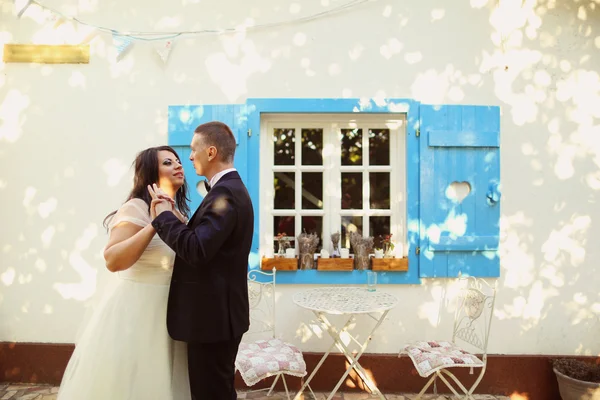 Nevěsta a ženich všeobjímající nedaleko krásného domu — Stock fotografie