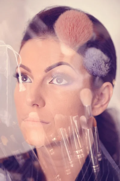 Красивая женщина с отражением кистей макияжа — стоковое фото
