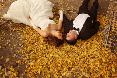 Gelin ve damat sonbahar yaprakları üzerinde döşeme
