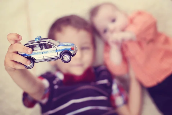 Anak laki-laki memegang mobil polisi dekat adik bayi — Stok Foto