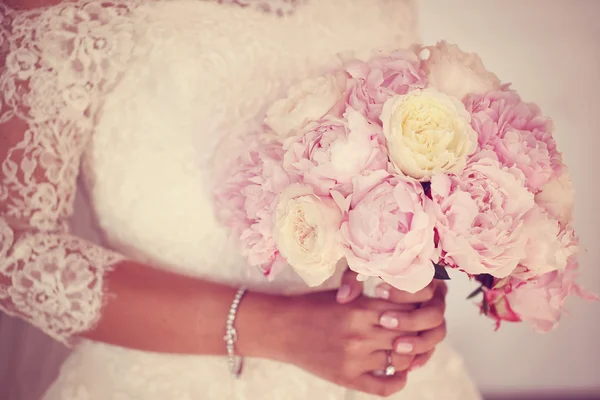 Hands of a bride holding peonies bouquet — Stock Photo, Image