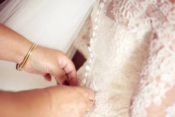 Mains aidant la mariée avec la robe de mariée — Photo