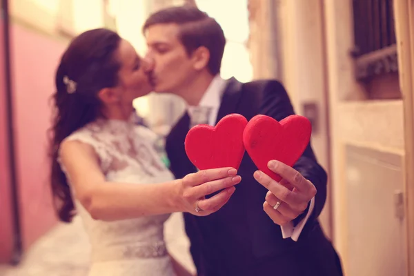 Bride and groom holding red hearts — Stock Photo, Image