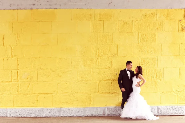 Mariée et marié contre mur jaune — Photo