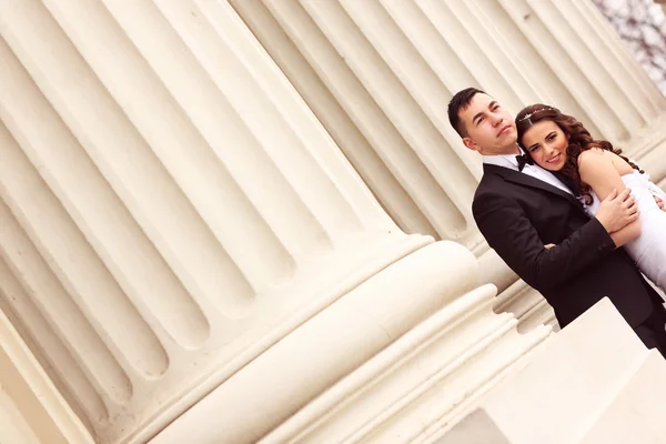 Bride and groom near white columns — Stock Photo, Image