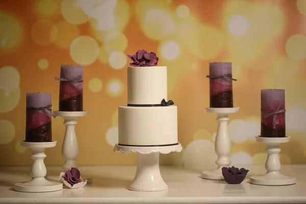 Gâteau de mariage blanc sorounded par des bougies violettes — Photo