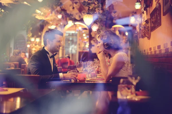 Bride and groom sitting on table at restaurant — Stock Photo, Image