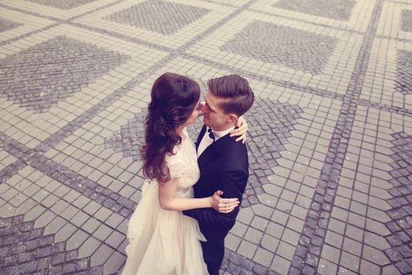 Bride and groom embracing on paved street — Stock Photo, Image