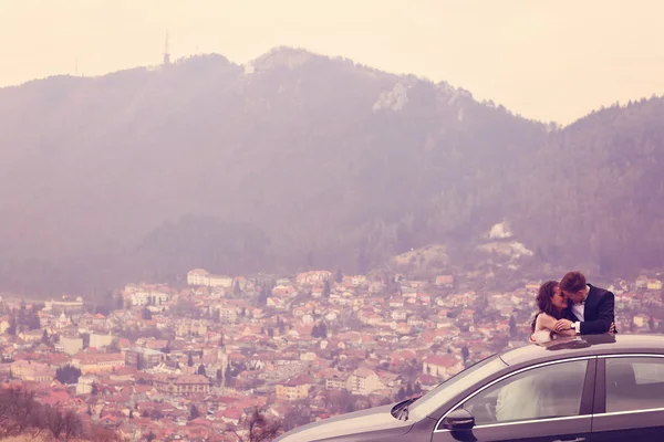 Bride and groom sitting on their car — Stock Photo, Image