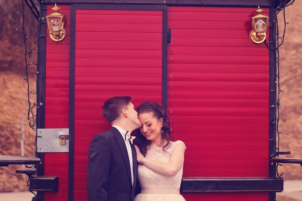 Bride and groom against red  door — Stock Photo, Image