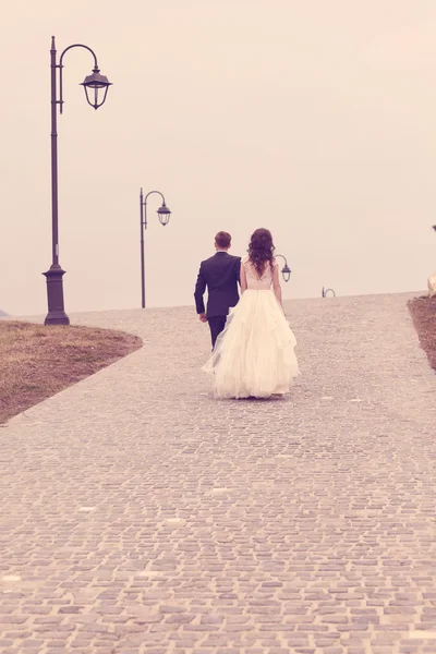 Bride and groom walking on pavement — Stock Photo, Image