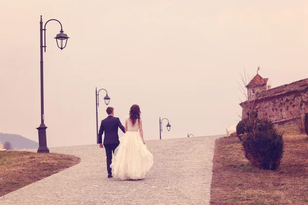 Bride and groom walking on pavement — Stock Photo, Image