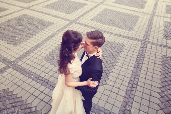 Noiva e noivo abraçando na rua pavimentada — Fotografia de Stock