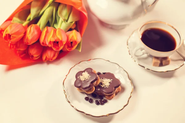 Leckerer Kuchen mit Kaffee und Tulpen auf dem Tisch — Stockfoto