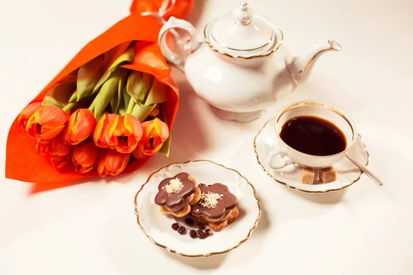 Leckerer Kuchen mit Kaffee und Tulpen auf dem Tisch — Stockfoto