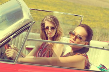 Güzel kadınlar accesoriess giyen bir kırmızı araba retro vintage sürüş