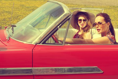Güzel kadınlar accesoriess giyen bir kırmızı araba retro vintage sürüş