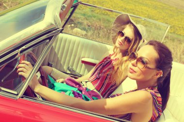 Güzel kadınlar accesoriess giyen bir kırmızı araba retro vintage sürüş