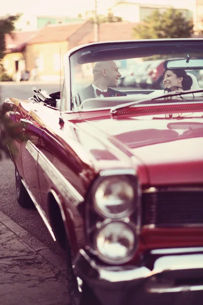 Les mariés s'amusent au volant d'une voiture vintage rétro rouge . — Photo