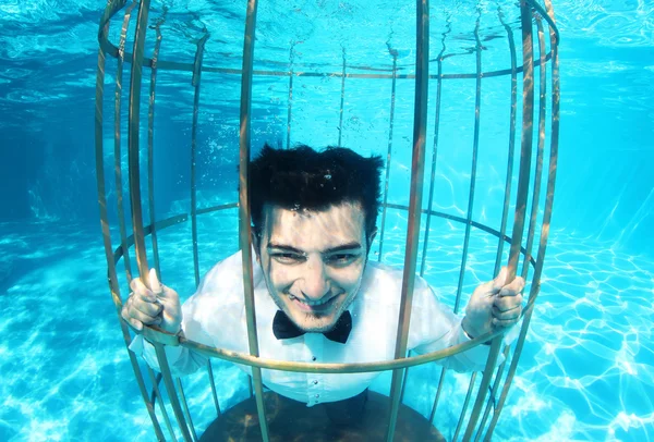 Funny groom underwater in a bird cage — Stock Photo, Image