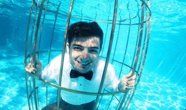 Divertido novio bajo el agua en una jaula de pájaros — Foto de Stock
