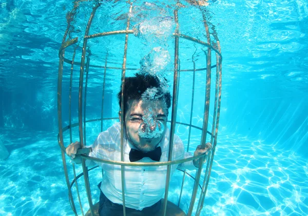 Funny groom underwater in a bird cage — Stock Photo, Image